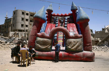 FILE PHOTO: Children play inside an inflatable castle during Eid al-Fitr celebration in the rebel-held besieged Douma neighbourhood of Damascus, Syria June 26, 2017. REUTERS/Bassam Khabieh/File Photo