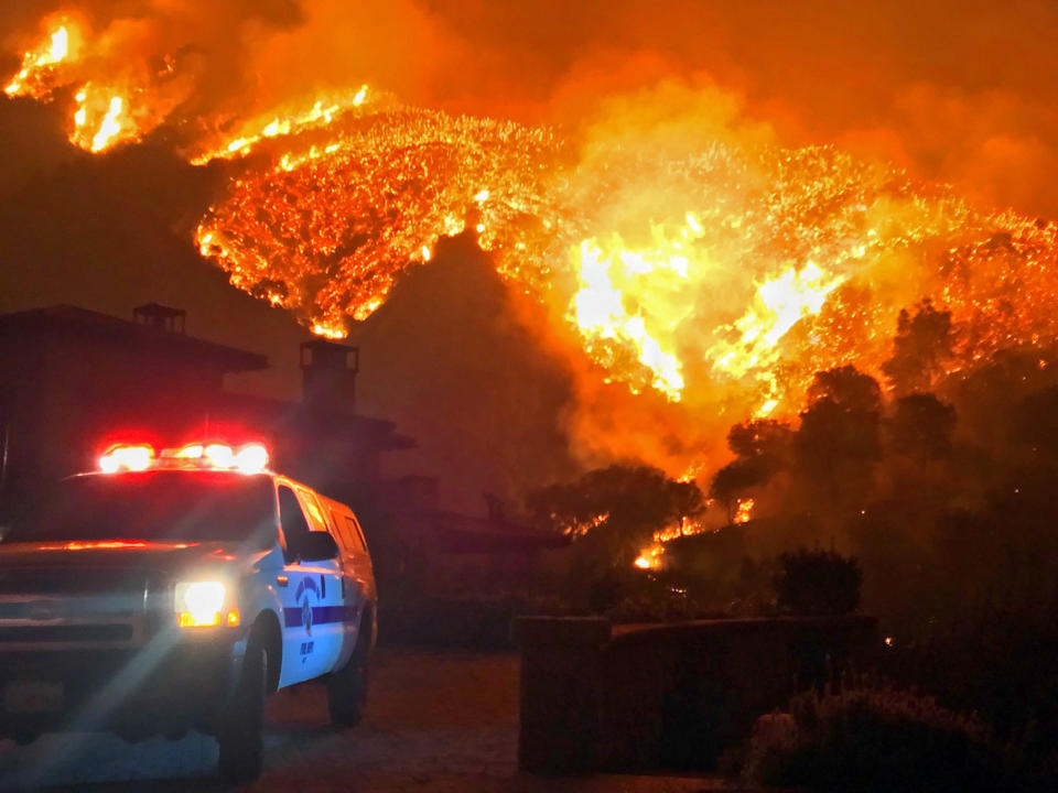 FILE - In this Dec. 12, 2017, file photo provided by the Santa Barbara County Fire Department, fire burns canyons and ridges above Bella Vista Drive near Romero Canyon as the fight to contain a wildfire continues in Montecito, Calif. An investigation has determined that one of the largest and most destructive fires in California history was sparked by power lines coming into contact during high winds. The Ventura County Fire Department says Wednesday that the contact ignited dry brush on Dec. 4, 2017 and eventually blackened more than 440 square miles (1,139 square kilometers). The Thomas fire destroyed more than a thousand structures in Ventura and Santa Barbara counties and resulted in the deaths of two people. (Mike Eliason/Santa Barbara County Fire Department via AP, File)