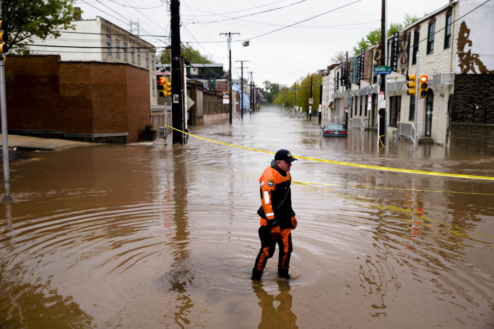 In this May 1, 2014 file photo, Marine unit police officer Robert Jonah walks through flood waters from the Schuylkill River on Main Street, Thursday, May 1, 2014, in the Manayunk neighborhood of Philadelphia. Global warming is rapidly turning America into a stormy and dangerous place, with rising seas and disasters upending lives from flood-stricken Florida to the wildfire-ravaged West, the National Climate Assessment report concluded Tuesday, May 6, 2014. (AP Photo/Matt Rourke)