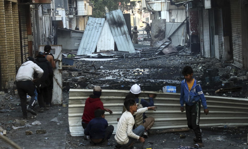 Anti-government protesters take cover during clashes with security forces in Baghdad, Iraq, Saturday, Nov. 30, 2019. (AP Photo/Hadi Mizban)