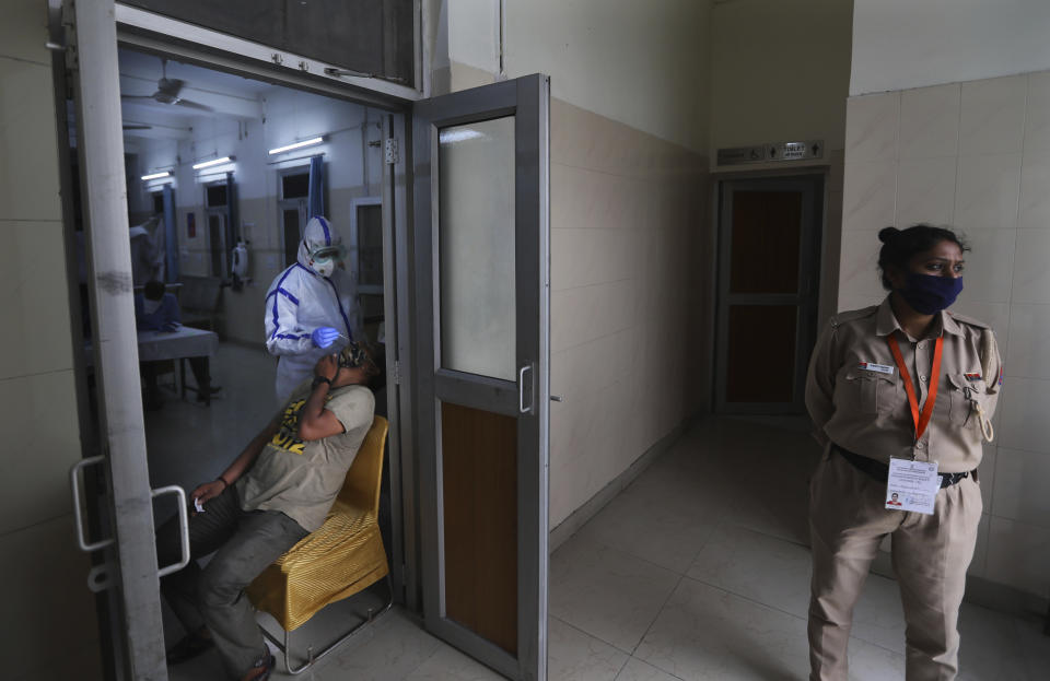 A health worker takes a nasal swab of a person for COVID-19 test as a policewoman stands guard at a local dispensary in New Delhi, India, Saturday, July 11, 2020. India has overtaken Russia to become the third worst-affected nation by the coronavirus pandemic. (AP Photo/Manish Swarup)