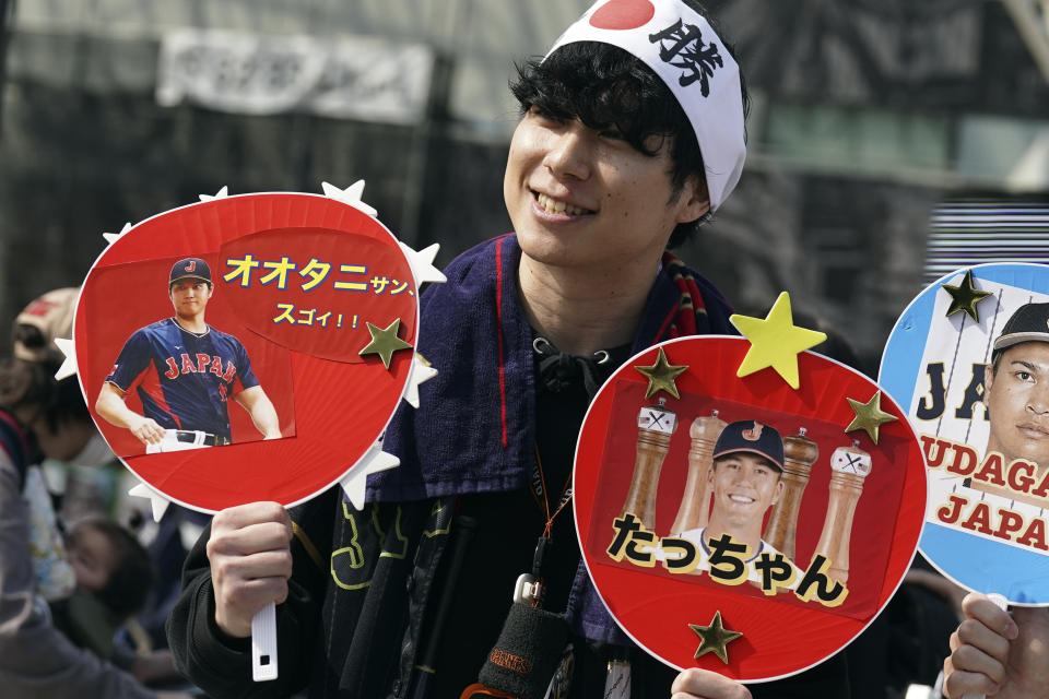 A fan of Japan's Shohei Ohtani and Lars Nootbaar cheer prior to the Pool B game between Japan and China at the World Baseball Classic (WBC) at the Tokyo Dome Thursday, March 9, 2023, in Tokyo. The paper fans read in Japanese "Mr. Ohtani Great !!" and "Tacchan (Japanese nickname for Nootbaar)." Japanese baseball player Shohei Ohtani is arguably the game's best player. But he's more than just a baseball player. He's an antidote for many in his native country. (AP Photo/Eugene Hoshiko)
