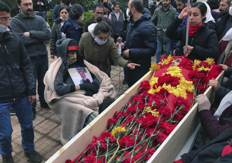 Mourners gather around the open coffin of Helin Bolek, a member of a popular folk music group that is banned in Turkey, during the funeral procession in Istanbul, Friday, April 3, 2020. Bolek died at home Friday on the 288th day of a hunger strike protesting the government's treatment of the band, in an effort to force the government to reverse its treatment of the band and its members. She was 28. Grup Yorum, known for its protest songs, is a folk collective with rotating band members, the government accuses the group of links to the outlawed Revolutionary People's Liberation Party-Front, or DHKP/C. (Ibrahim Mase/DHA via AP)