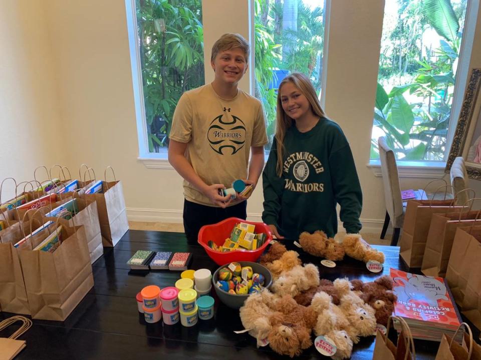 Devin Maier, left, president of the Connect4Cancer club at Westminster Christian School, with his sister, Dylan Maier, and a few of the items that the two used to prepare craft bags for children at the Ronald McDonald House. The craft bags included coloring books, crayons, notepads, teddy bears and Play-Doh.