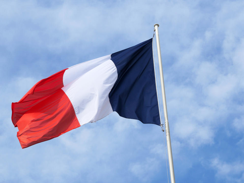 The French flag flies in the winds on a pole at the Elysee Palace in Paris, France. Cloudy sky. Light and natural colors.