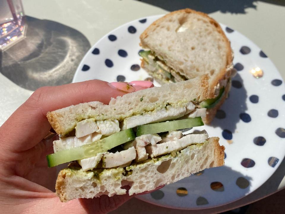 A sourdough sandwich with chicken, pesto, cream cheese, and cucumber.