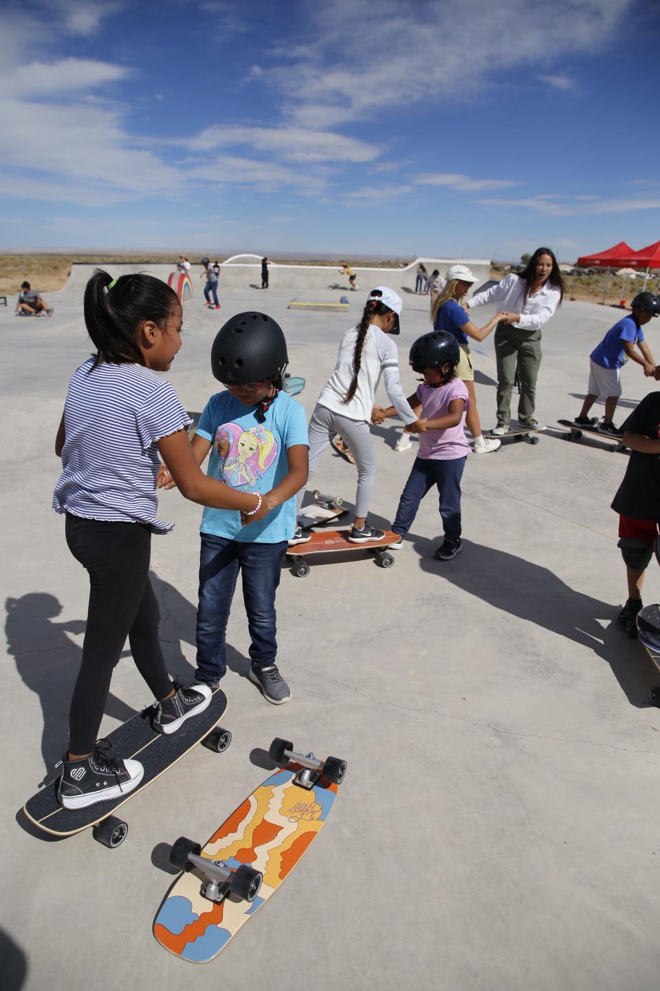 Participants in a skateboarding clinic work with a partner to learn the proper way to mount a skateboard during the opening session of the Modern Matriarch Skate Jam Friday, Sept. 22 at the Two Grey Hills Skate Park in Two Grey Hills.