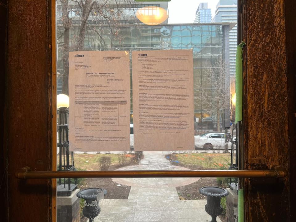 City of Toronto documents posted on the front door of the apartment detail two property standards violations for failing to provide every unit with hot water and heat.