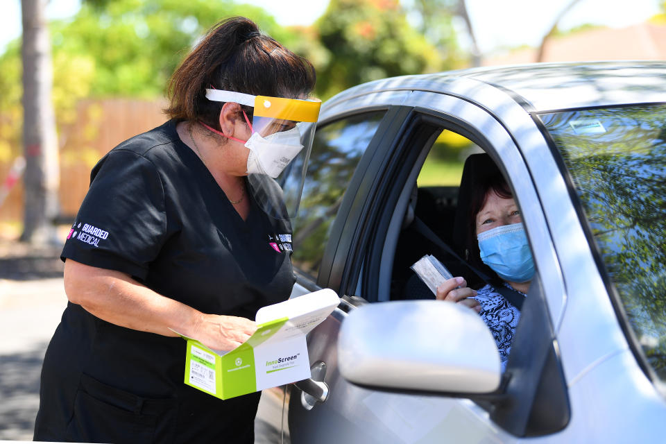 Maria Scafi, the site lead at the Rapid Antigen Test Kit Distribution centre hands out a Rapid Antigen Test Kit at the Sunshine West Community Centre in Melbourne. Source: AAP