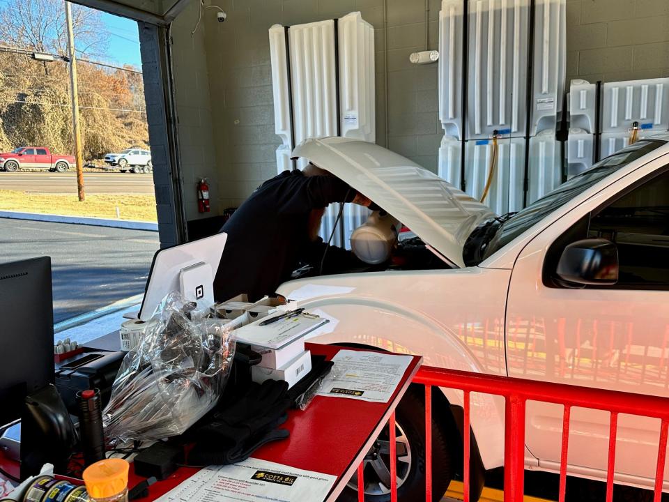 Assistant Manager Chris Burton pours new oil into a customer's vehicle at the new Costa Oil Chapman Highway location on Nov. 16, 2023.