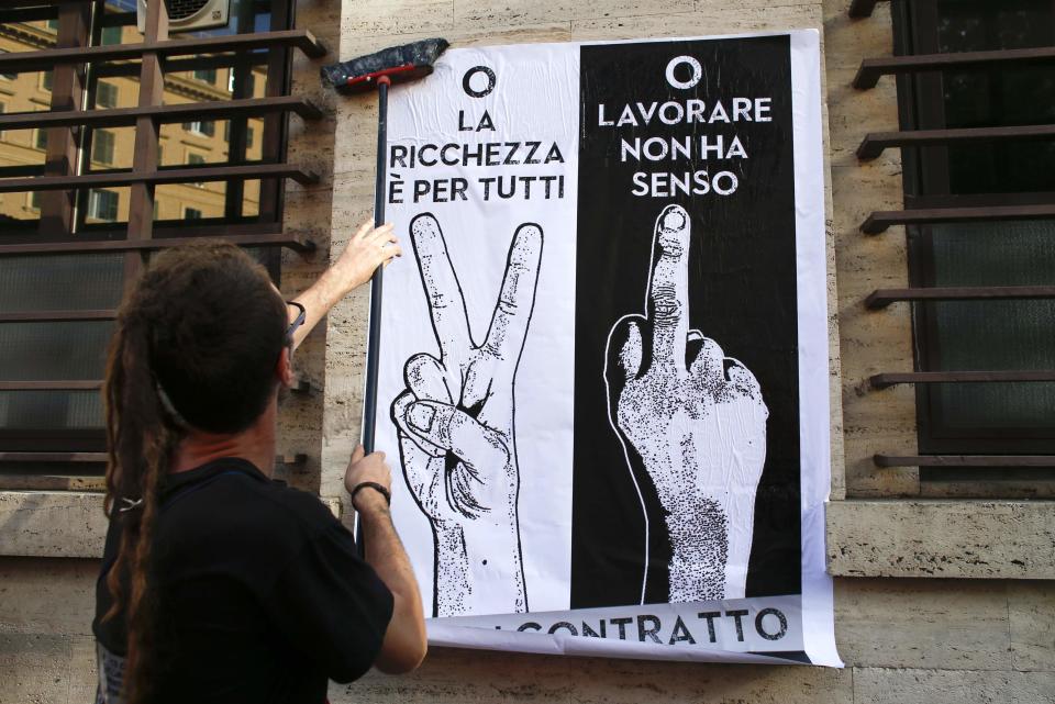 A demonstrator glues a banner on a wall during a protest in downtown Rome