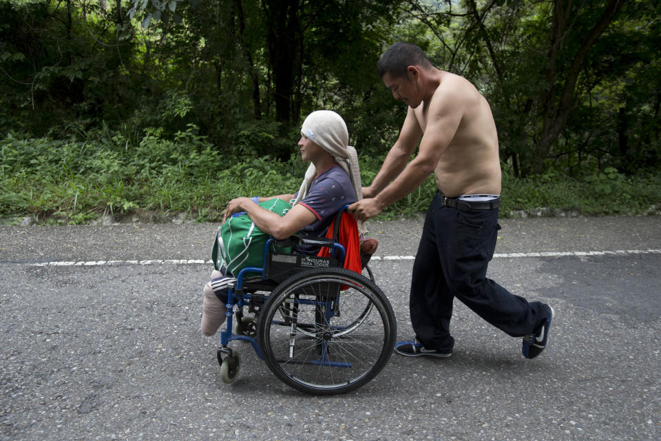 Honduran migrant Omar Orella pushes fellow migrant Nery Maldonado Tejeda in a wheelchair, as they travel with hundreds of other Honduran migrants making their way the U.S., near Chiquimula, Guatemala, on Tuesday, Oct. 16, 2018. Maldonado said he lost his legs in 2015 while riding "The Beast," a northern-bound cargo train that crosses Mexico, and that this is his second attempt to reach the U.S. (AP Photo/Moises Castillo)