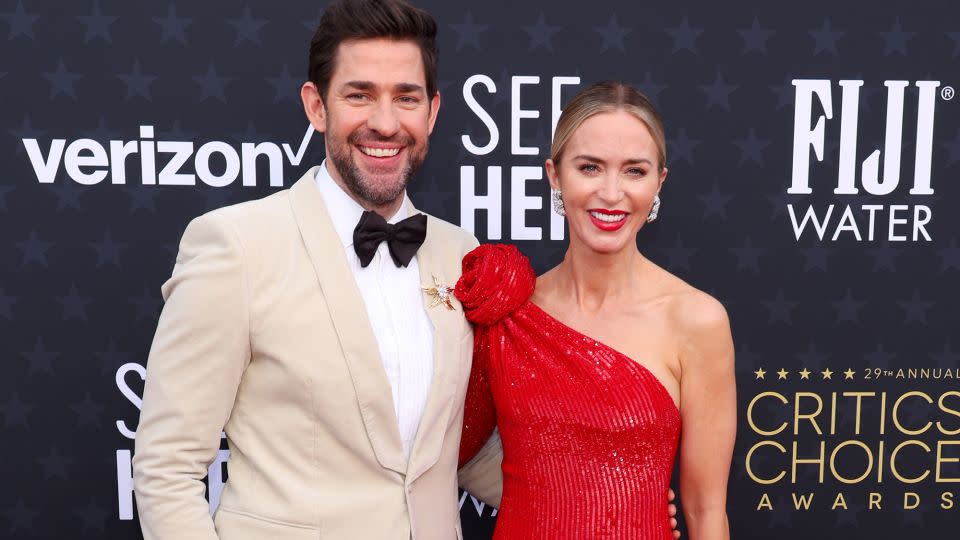 John Krasinski wore an off-white Dolce & Gabbana tuxedo jacket with black pants and bowtie, while Emily Blunt was in a sleek red Giorgio Armani Privé dress with a rosette detail and Tiffany & Co. jewelry. - Matt Winkelmeyer/Getty Images