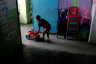 A kid pushes a toy cart next to a stack of chairs in a classroom on the first day of school, in Caucagua, Venezuela September 17, 2018. REUTERS/Marco Bello