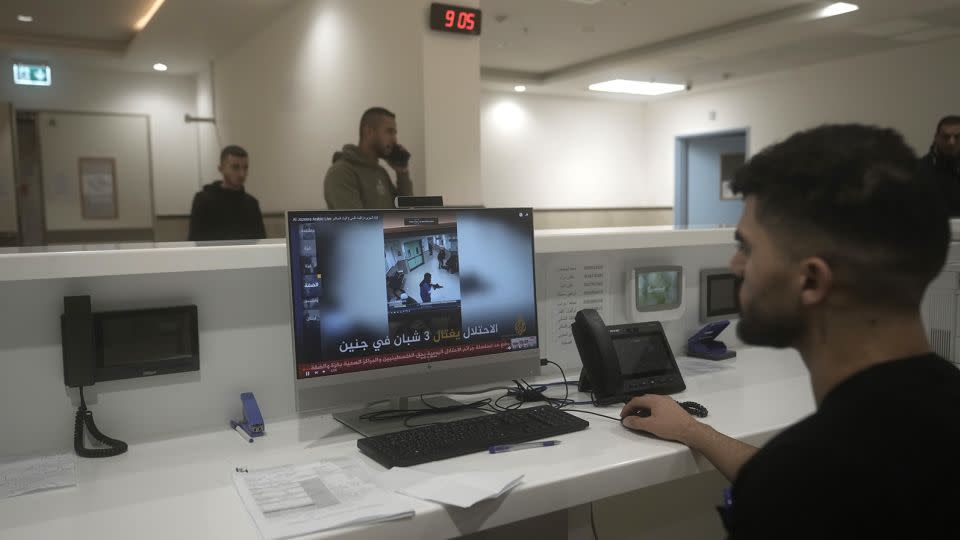 A staff member at Ibn Sina hospital shows a news broadcast of CCTV footage showing Israel's deadly raid. - Majdi Mohammed/AP
