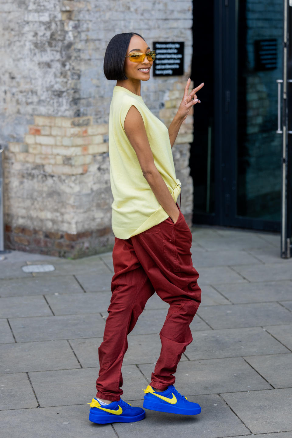 Jourdan Dunn wears yellow sleeveless top, red pants, Nike Airforce 1 sneakers, and sunglasses outside JW Anderson during London Fashion Week Fall 2023 on February 19, 2023 in London, England. (Photo by Christian Vierig/Getty Images) - Credit: Getty Images