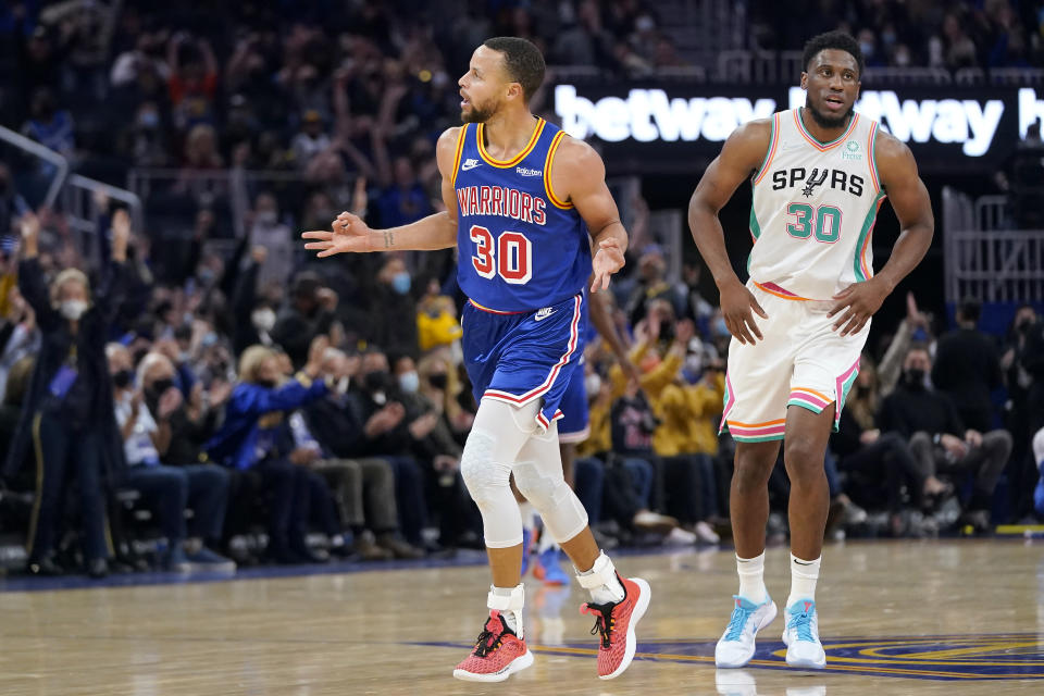 Golden State Warriors guard Stephen Curry, left, gestures after shooting a 3-point basket in front of San Antonio Spurs forward Thaddeus Young during the first half of an NBA basketball game in San Francisco, Saturday, Dec. 4, 2021. (AP Photo/Jeff Chiu)