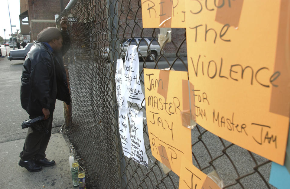 FILE - James Charles Daniels grieves against a fence that served as a makeshift memorial for pioneering rapper Jam Master Jay, Thursday, October 31, 2002, near a recording studio in the Queens borough of New York where he was killed. Opening statements are set for Monday in the federal murder trial of Karl Jordan Jr. and Ronald Washington, who were arrested in 2020 for the murder of Jam Master Jay. (AP Photo/Robert Mecea)