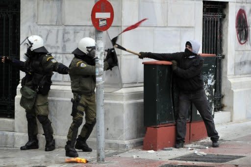 Riot police clash with a demonstrator during a 48-hour general strike in Athens. Greece's cabinet Saturday approved tough austerity measures demanded by EU and IMF creditors after the prime minister warned that a failed debt deal and default would spark "uncontrolled chaos"