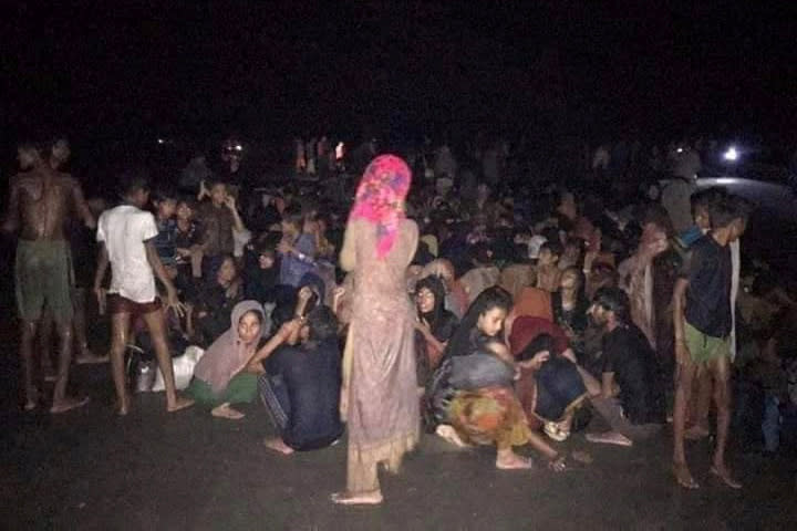 Rohingya refugees who were rescued by Bangladesh Coast Guard, sit on the shore in Teknaf
