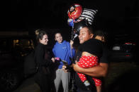 Walfrido Fuentes holds Madisson next to the little girl's mother, Melanie Rolo Gonzalez, center, whose sister Merlyn stands with her in Daytona, Florida, Tuesday, Jan. 3, 2023. Days before, the child and the two young women crossed the U.S.-Mexico border, three weeks after leaving Cuba to migrate to the U.S. The three are staying in Fuentes' home. His wife is an old friend of the women’s mother. (AP Photo/Marta Lavandier)