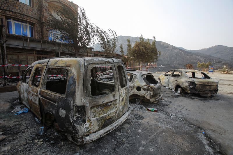 Burnt vehicles are pictured in the aftermath of a wildfire in Bejaia