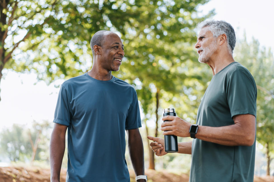 Senior friends pause to chat while walking in public park