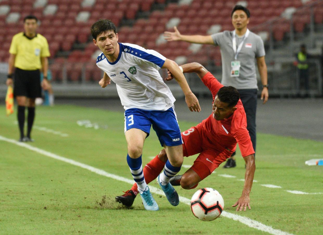 Singapore's Muhammad Hafiz Noh (red jersey) battles for the ball with Uzbekistan's Farrukh Sayfiev in the 2022 World Cup qualifying clash at the National Stadium. (PHOTO: Zainal Yahya/Yahoo News Singapore)