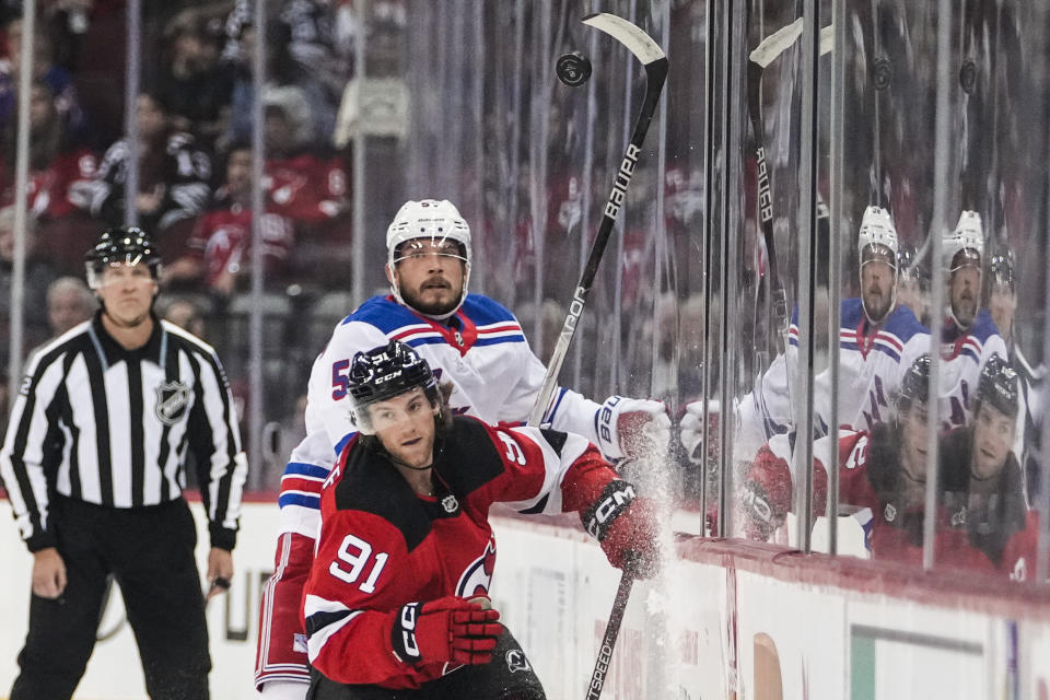New Jersey Devils' Dawson Mercer (91) vies for control of the puck with New York Rangers' Ryan Lindgren (55) during the first period of an NHL preseason hockey game Wednesday, Oct. 4, 2023, in Newark, N.J. (AP Photo/Frank Franklin II)