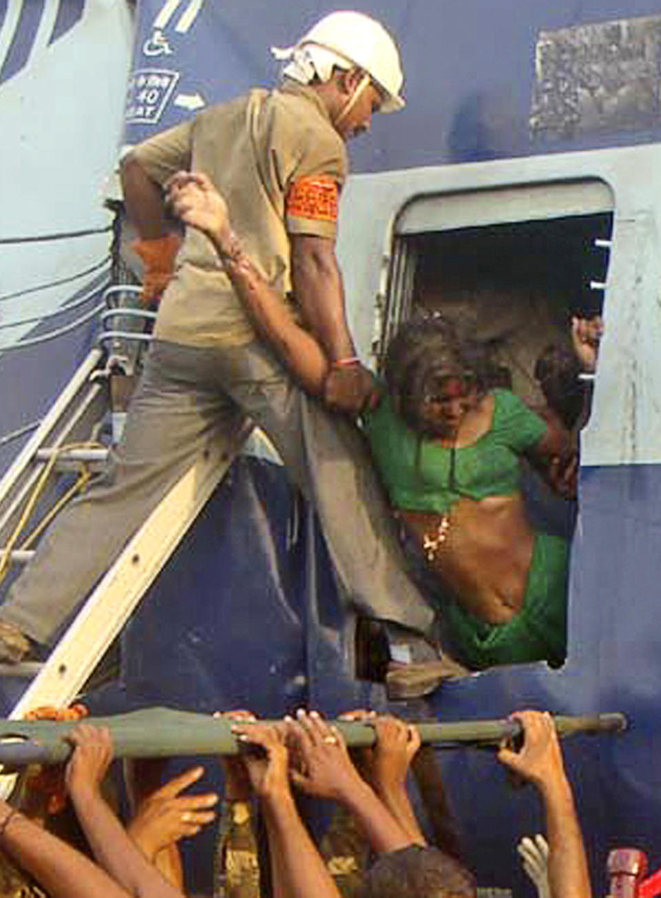 ALTERNATE CROP OF DEL114 - Rescuers evacuate an injured woman from the site of a train accident at a station near Penukonda, about 170 kilometers (105 miles) north of Bangalore, India, Tuesday, May 22, 2012. The passenger train rammed into a parked freight train and burst into flames before dawn Tuesday, killing more than a dozen people in southern India, officials said. (AP Photo)