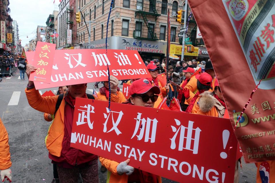 People carry signs in support of Wuhan, China, at the center of the coronavirus outbreak, during the Lunar New Year parade on Feb. 9, 2020, in Manhattan's Chinatown.