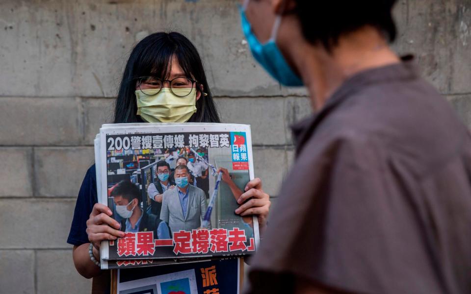 A volunteer poses holding a copy of the Apple Daily newspaper -  ISAAC LAWRENCE/AFP via Getty Images