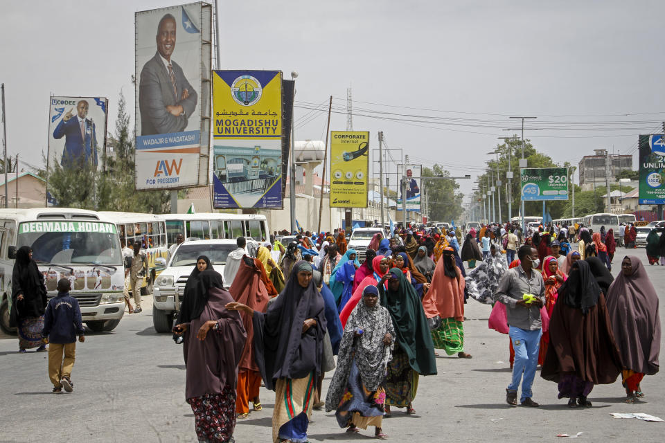 Somalis walk past billboards showing candidates Abdirahman Abdishakur Warsame and Omar Abdulkadir Ahmedfiqi in Mogadishu, Somalia Friday, Jan. 29, 2021. As Somalia marks three decades since a dictator fell and chaos engulfed the country, the government is set to hold a troubled national election but two regional states are refusing to take part in the vote to elect Somalia's president and time is running out before the Feb. 8 date on which mandates expire. (AP Photo/Farah Abdi Warsameh)