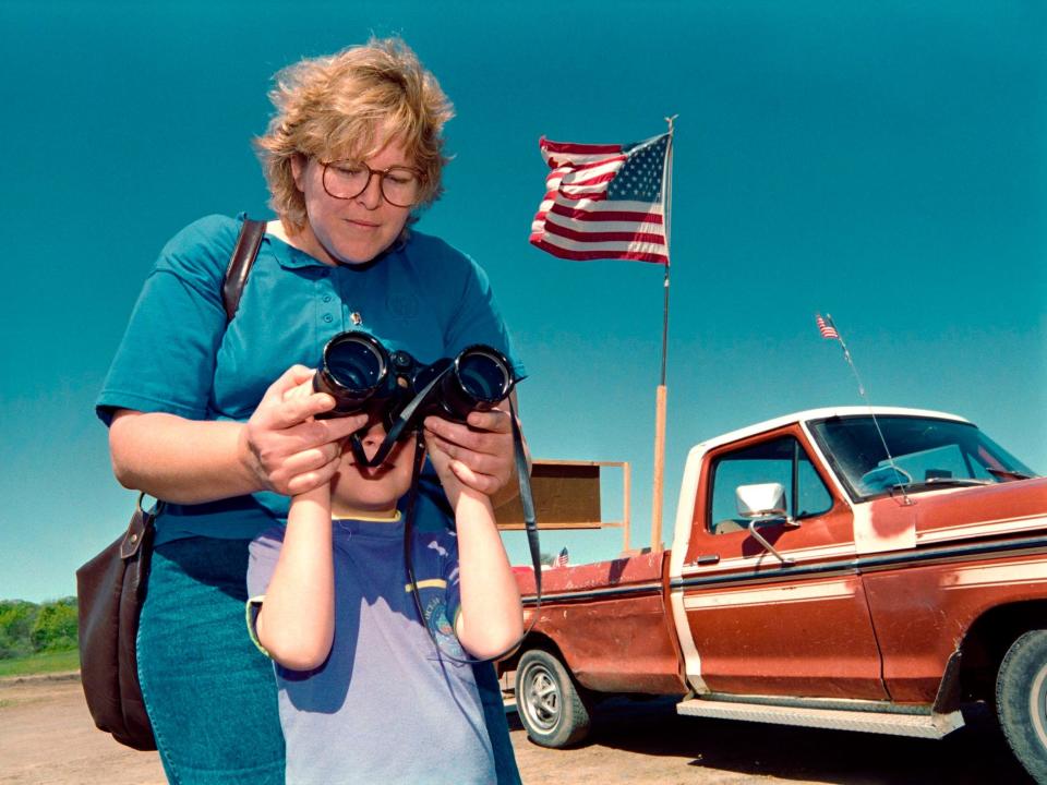 A boy and his aunt watch the Branch Davidian compound through a pair of binoculars in 1993 from a nearby hill.