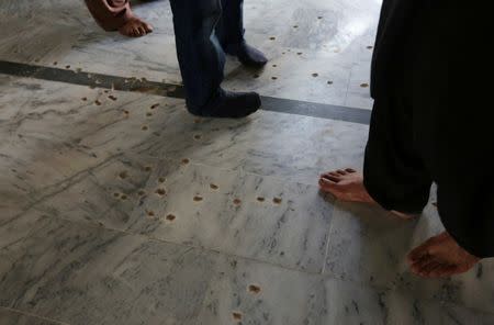 Residents walk on a floor scarred by shrapnel, which witnesses said was damaged in a suicide blast on January 2015, in a Shi'ite mosque in Shikarpur, Pakistan March 19, 2017. Picture taken March 19, 2017. REUTERS/Akhtar Soomro