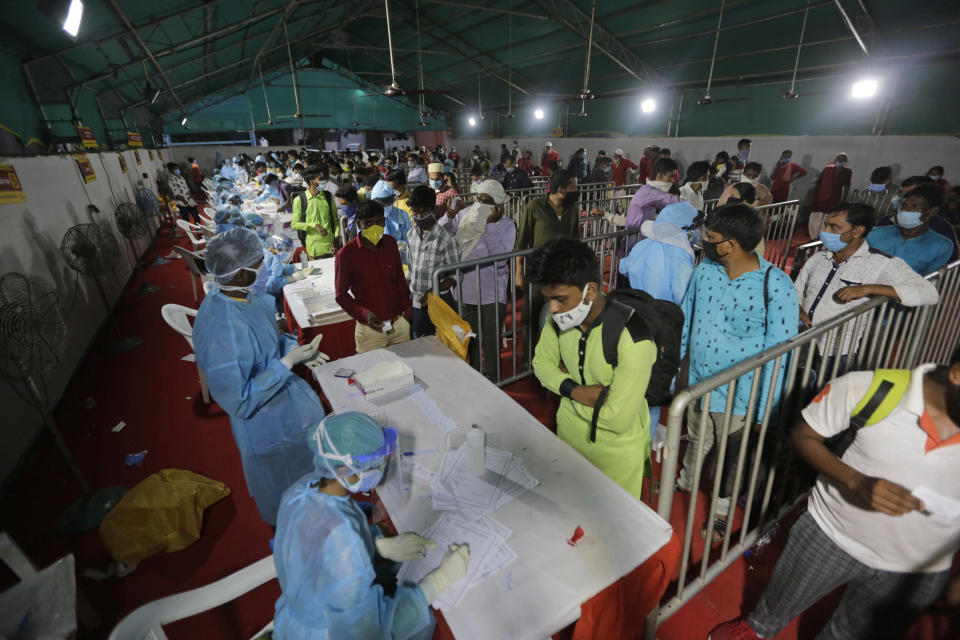 Indian passengers queue up to test for COVID-19 at a facility erected at a railway station to screen people coming from outside the city, in Ahmedabad, India, Friday, Sept. 18, 2020. India's coronavirus cases jumped by another 96,424 in the past 24 hours, showing little sign of leveling. India is expected to have the highest number of confirmed cases within weeks, surpassing the United States, where more than 6.67 million people have been infected. (AP Photo/Ajit Solanki)