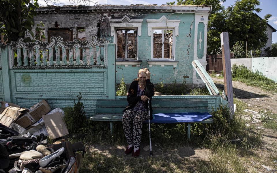 A woman sits on a bench in front of a destroyed building as the residents of Andriivka village try to maintain their lives under difficult conditions - Metin Aktas/Anadolu Agency via Getty Images