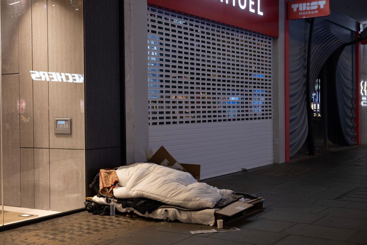 Homeless people sleeping on the pavement outside retails chain stores store along Oxford Street, London, England