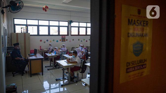 Guru memberi materi kepada siswa saat pembelajaran tatap muka (PTM) di SDN 01 Pondok Labu, Jakarta, Senin (3/1/2022). Pemprov DKI Jakarta menggelar pembelajaran tatap muka (PTM) setiap hari dengan jumlah siswa setiap kelas mencapai 100 persen dari kapasitas. (Liputan6.com/Faizal Fanani)
