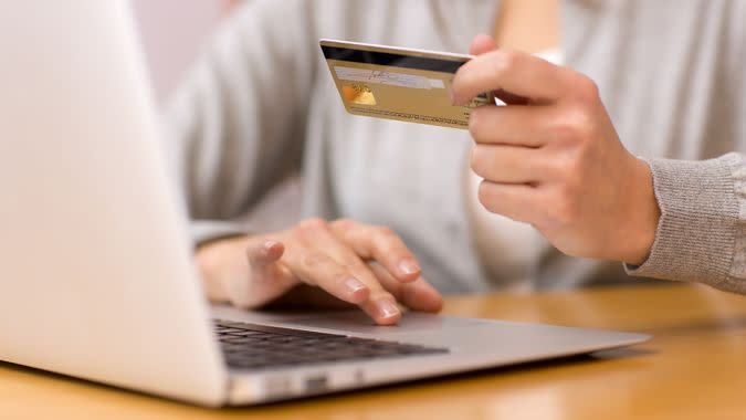 Close-up woman's hands holding a credit card and using computer keyboard for online shopping.