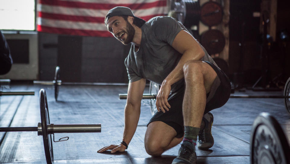  Man kneeling next to dumbbell, resting. 