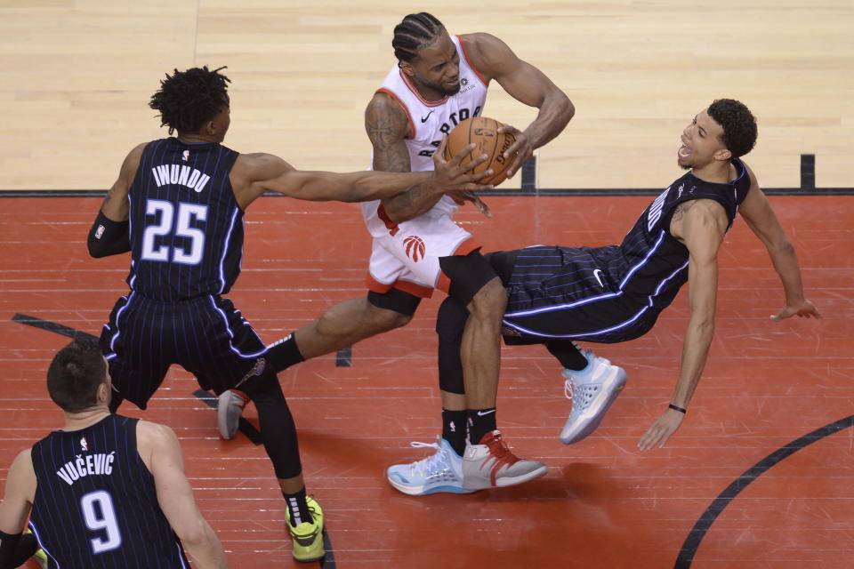 Toronto Raptors forward Kawhi Leonard (2) picks up an offensive foul on Orlando Magic forwards Jonathan Isaac (1) as forward Wes Iwundu (25) looks on during the second half in Game 1 of a first-round NBA basketball playoff series in Toronto, Saturday, April 13, 2019. (Nathan Denette/The Canadian Press via AP)
