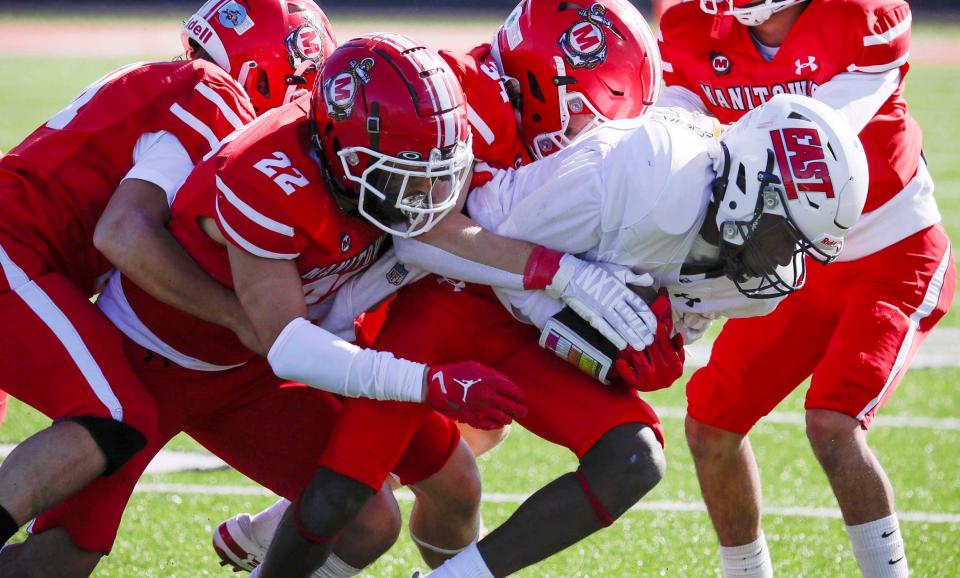 Green Bay East’s Quearay Woods (1) is pulled down by a squad of Manitowoc Lincoln players on Saturday at Ron Rubick Field in Manitowoc.