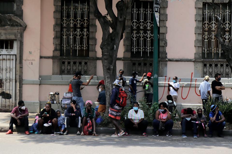 Haitian migrants sit on the pavement outside the Mexican Commission for Refugee Support in Mexico City