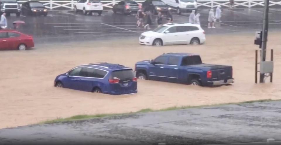 People rush through a parking lot at Dollywood as floodwaters stream through the theme park (TMX)