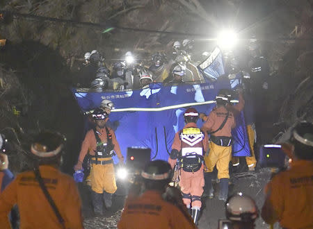 Firefighters carry a missing person found from an area damaged by a landslide caused by an earthquake in Atsuma town, Hokkaido, northern Japan, in this photo taken by Kyodo September 8, 2018. Mandatory credit Kyodo/via REUTERS