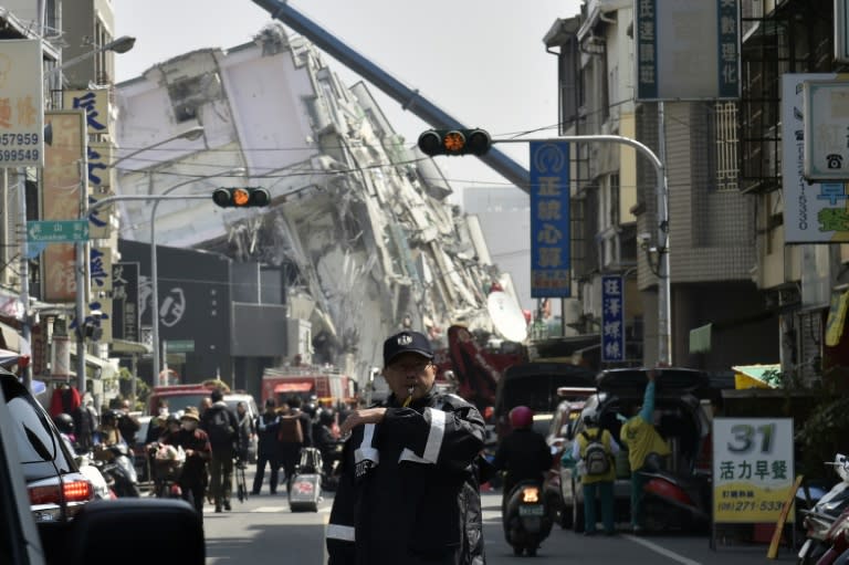 Police direct traffic near a collapsed building on February 7, 2016, after a 6.4 magnitude earthquake struck southern Taiwan