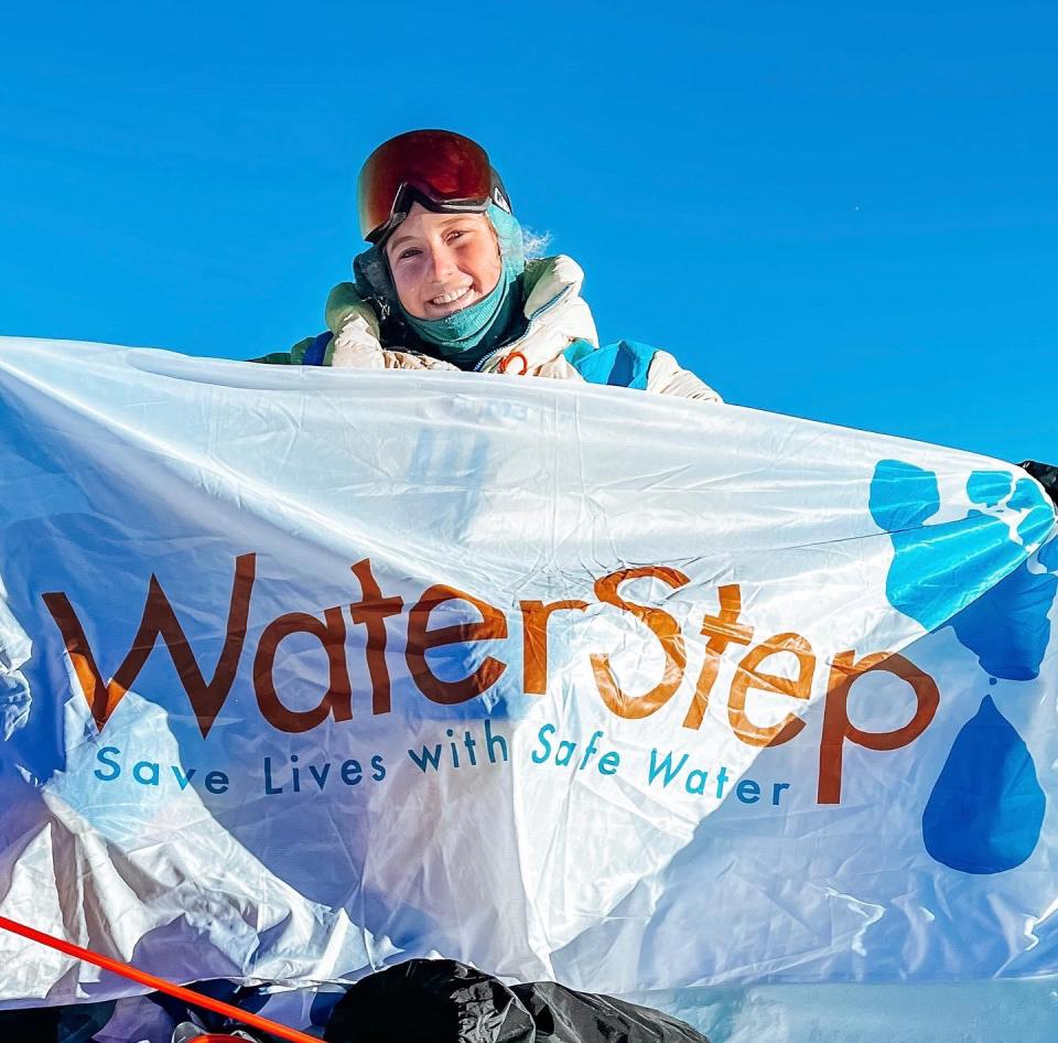 Lucy Westlake holding a WaterStep flag at the summit of Mount Everest.