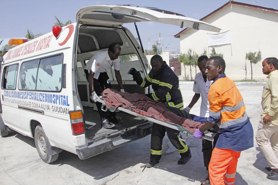 Medics carry away a victim at the scene of a bomb blast near the presidential palace, Saturday, Dec. 22, 2018. Police say a suicide car bomb detonated near the presidential palace killing and injuring a number of people. (AP Photo/Farah Abdi Warsameh)