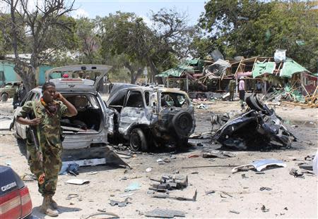 A Somali soldier walks past destroyed vehicles at the scene of a suicide car bombing near a restaurant in Hamaerweyne district in Mogadishu September 7, 2013. A car bomb and suspected suicide bomber struck the restaurant in the Somali capital Mogadishu on Saturday, killing at least 15 people, police said. REUTERS/Feisal Omar